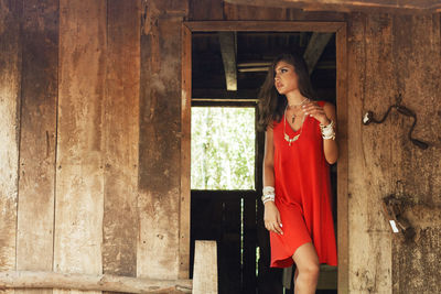 Woman in red dress standing at abandoned house