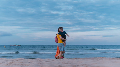 Full length of woman standing at beach against sky