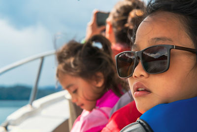 Young girl wearing sunglasses on a boat with family. vacation, travel and active kid concept.