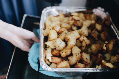 Cropped hand baking potatoes in oven