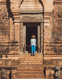 Rear view of woman walking on staircase against building