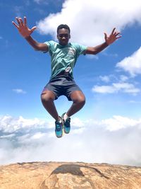 Low angle view of man jumping against sky