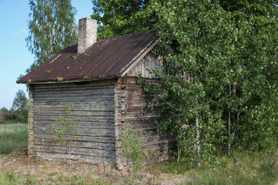 Old wooden house amidst trees and plants