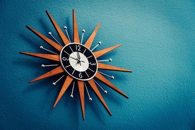 Directly above shot of clock on table against blue wall