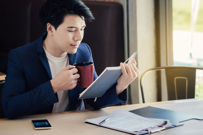 Young man using mobile phone while sitting on table