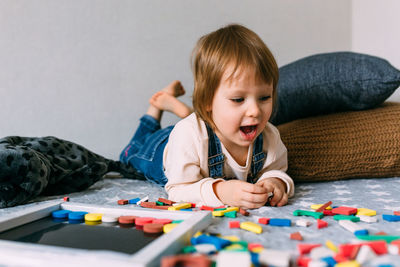 Child plays at home an educational game with a multi-colored magnetic puzzle