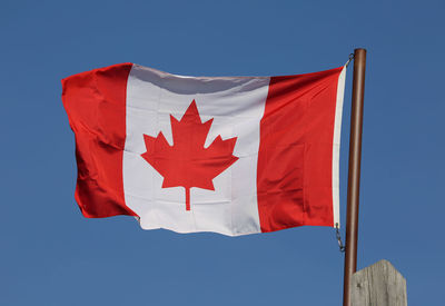 Low angle view of flag on red against clear blue sky