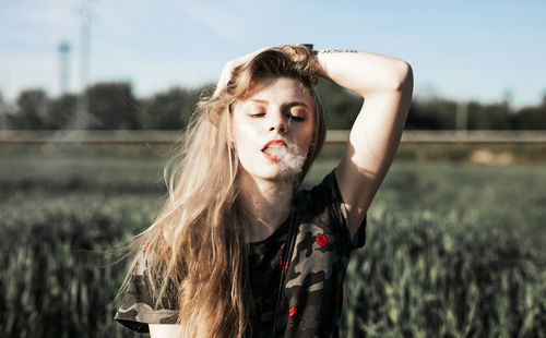 Young woman smoking on field