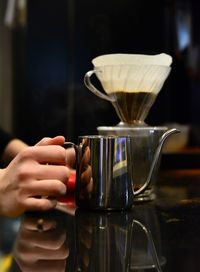 Cropped hands of bartender holding mug on table in cafe