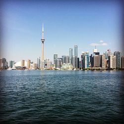 Sea against cn tower amidst modern buildings in city