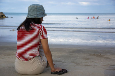 Rear view of woman sitting at beach