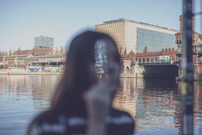 Double exposure of young woman and buildings by river in city