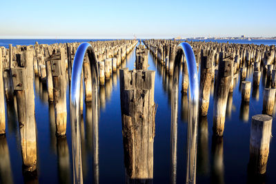 Panoramic shot of wooden posts in sea against clear sky