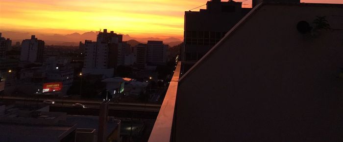 Illuminated cityscape against sky during sunset