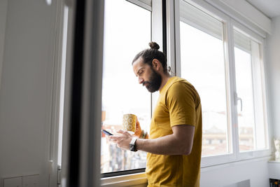 Side view of young man looking through window