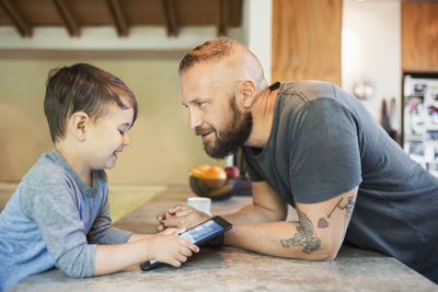 Father and son sitting on table