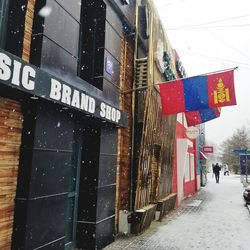 Road sign on street amidst buildings in city during winter