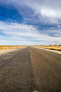 View of road amidst agricultural landscape against sky