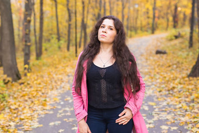 Beautiful young woman standing in forest during autumn