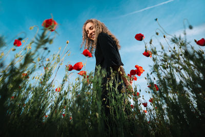 Woman standing on red flowering plants