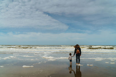 Woman standing on beach against sky