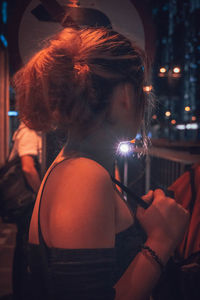 Portrait of woman holding illuminated lighting equipment at night