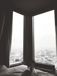 Low section of person lying on bed by windows in apartment