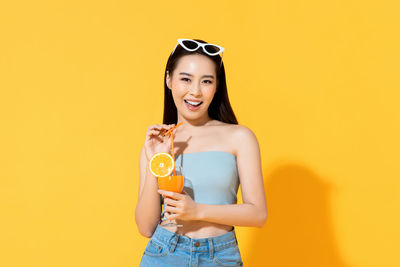 Portrait of a smiling young woman against yellow background