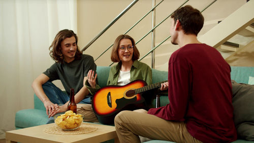 Cheerful woman with guitar talking with friends