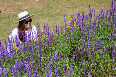 High angle view of smiling beautiful woman touching flowers