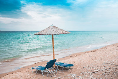 Deck chairs on beach against sky