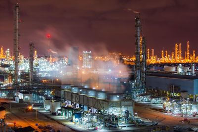 Illuminated factory against sky at night