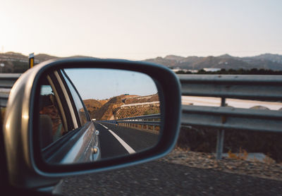 Close-up of side-view mirror against clear sky