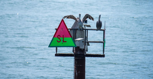 Close-up of sign board against sea