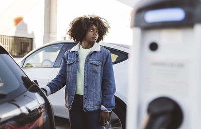 Woman recharging electric car at charging station