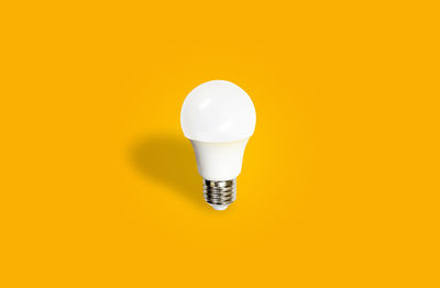 Close-up of light bulb against yellow background