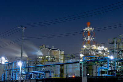 Illuminated factory against sky at night