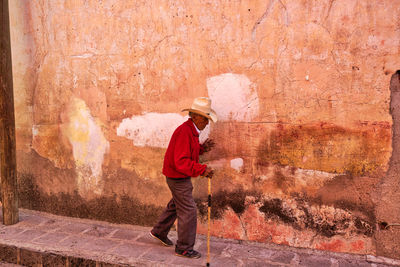 Side view of man standing against wall