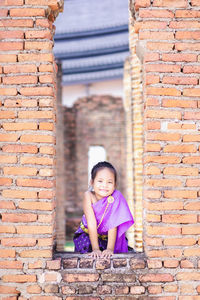 Portrait of girl standing against brick wall