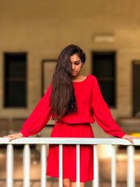 Young woman with red umbrella standing against blurred background