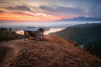 Abandoned house on field against sky during sunset
