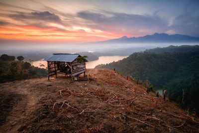 Abandoned house on field against sky during sunset