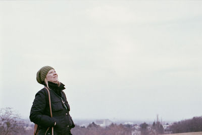 Mature woman wearing warm clothing while looking away against sky during winter