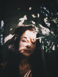 Portrait of young woman against tree