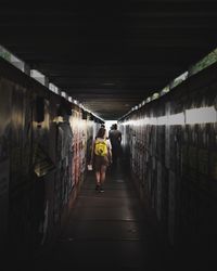 Rear view of people walking in illuminated tunnel