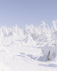 Snow covered land against clear sky