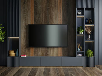 Wooden wall mounted tv in modern living room with decoration on dark wall background.3d rendering