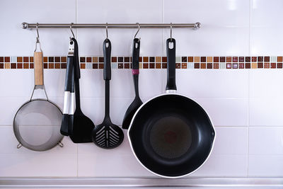 Cooking utensils hanging on rack on tiled wall