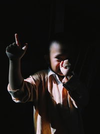 Portrait of man with arms raised standing in darkroom