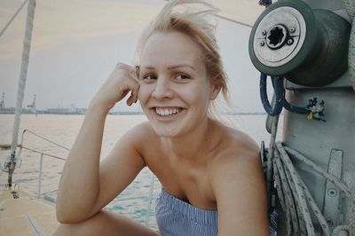 Portrait of cheerful young woman on boat in sea during sunset